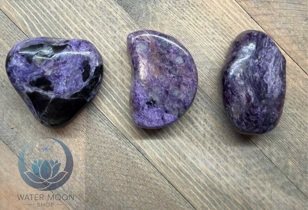 Three purple tumbled stones on a wooden surface with 'Water Moon Shop' logo.