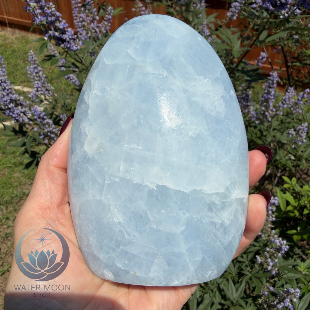 Large blue stone held in a hand with a blurred natural background
