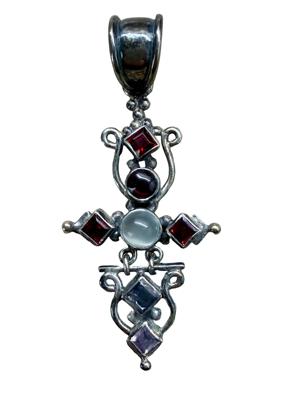 Silver cross pendant with embedded gemstones on a wooden surface