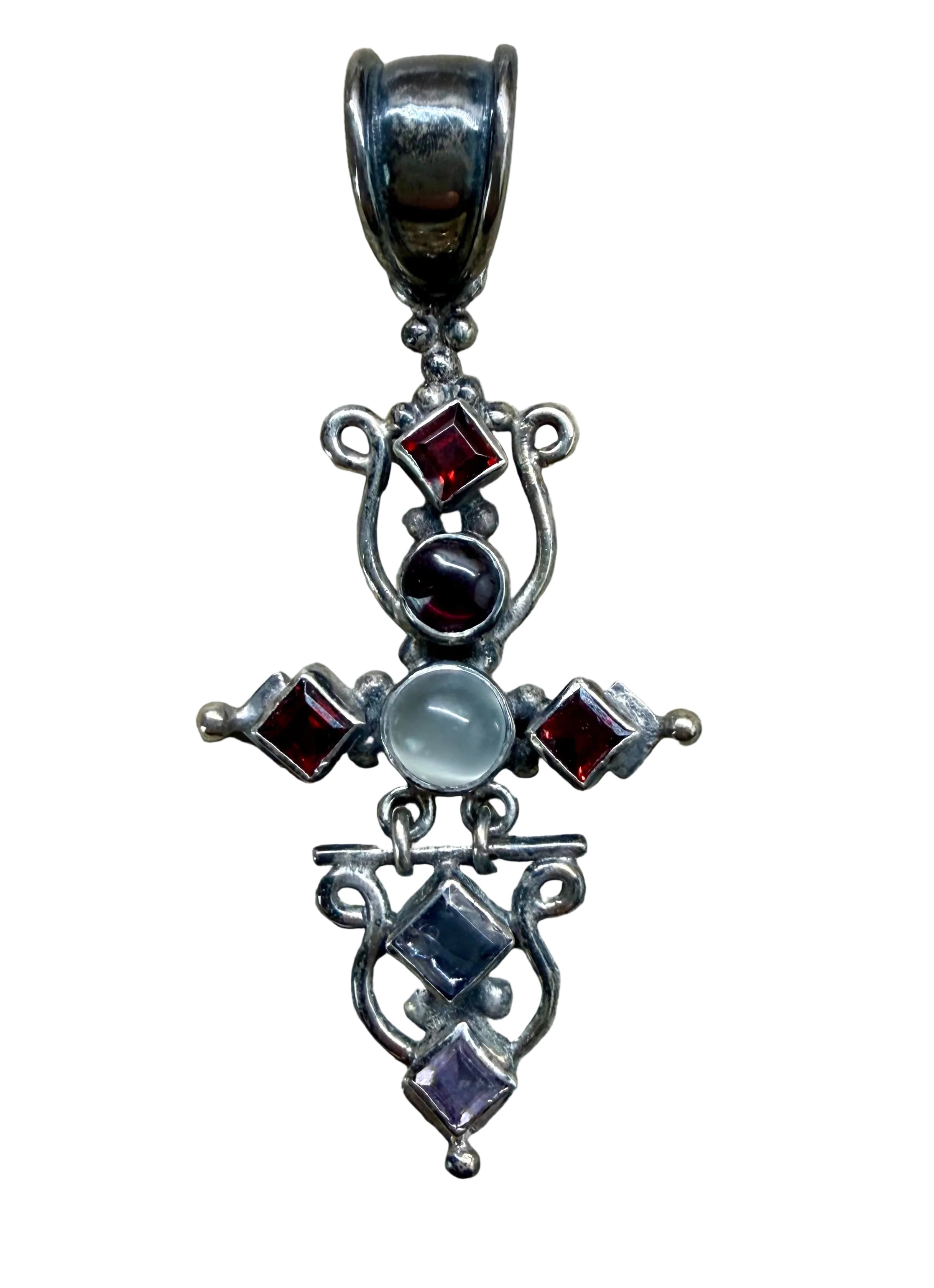 Silver cross pendant with embedded gemstones on a wooden surface
