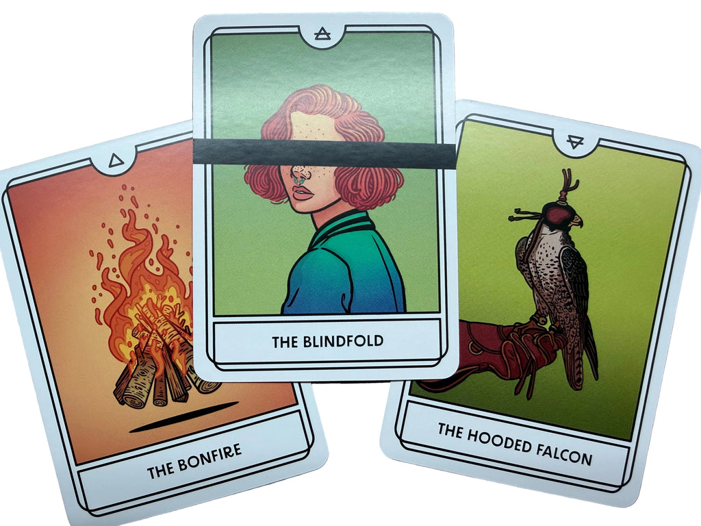 Three tarot cards titled 'The Bonfire', 'The Lindoid', and 'The Hoofed Falcon' on a wooden surface.