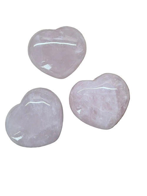 Three pink rose quartz stones on a wooden surface