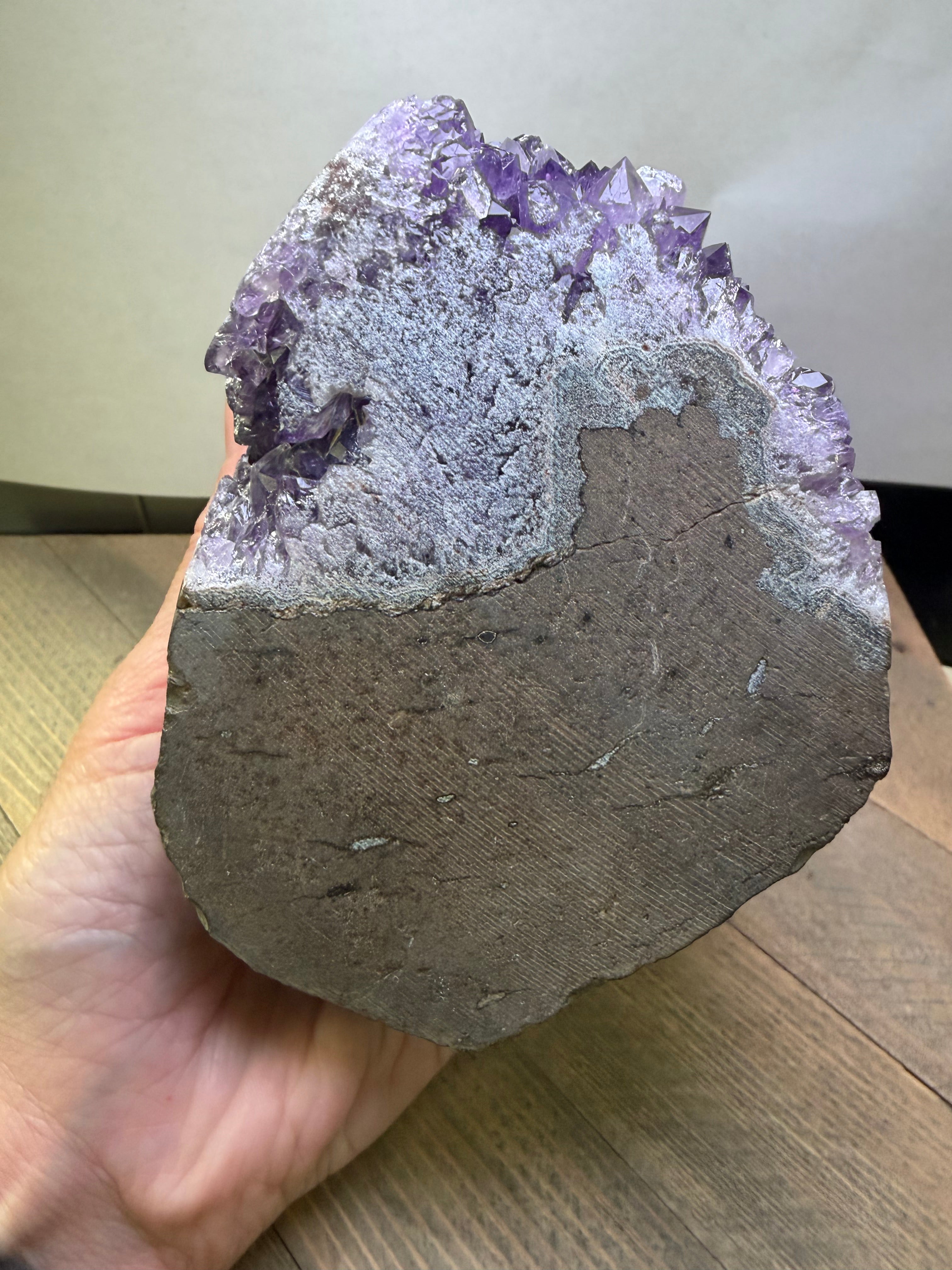Amethyst geode held in a hand with a neutral background