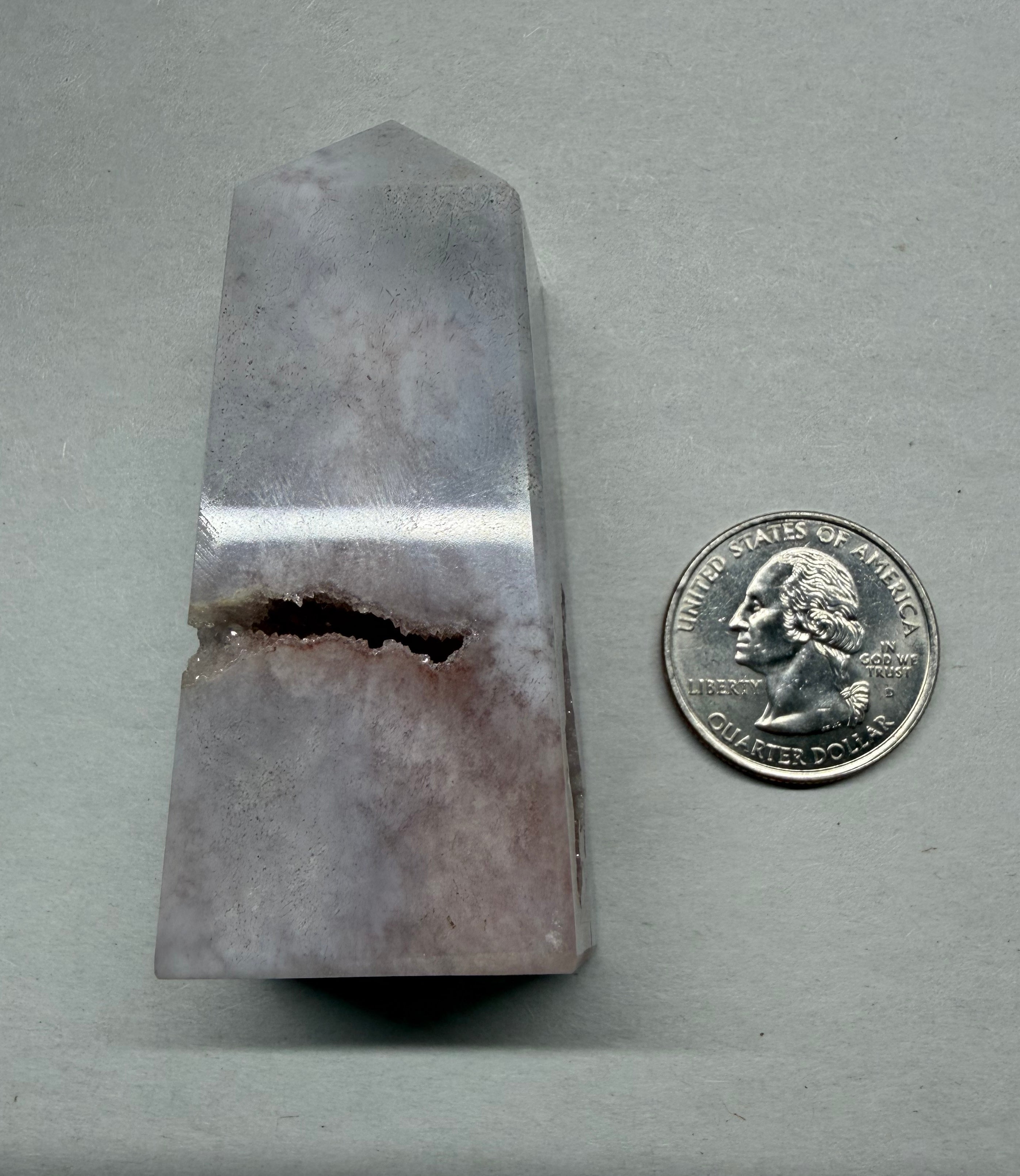 Crystal prism next to a U.S. quarter on a gray background