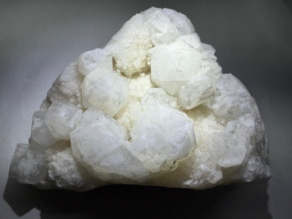 A cluster of large, translucent white crystals on a dark gray background.