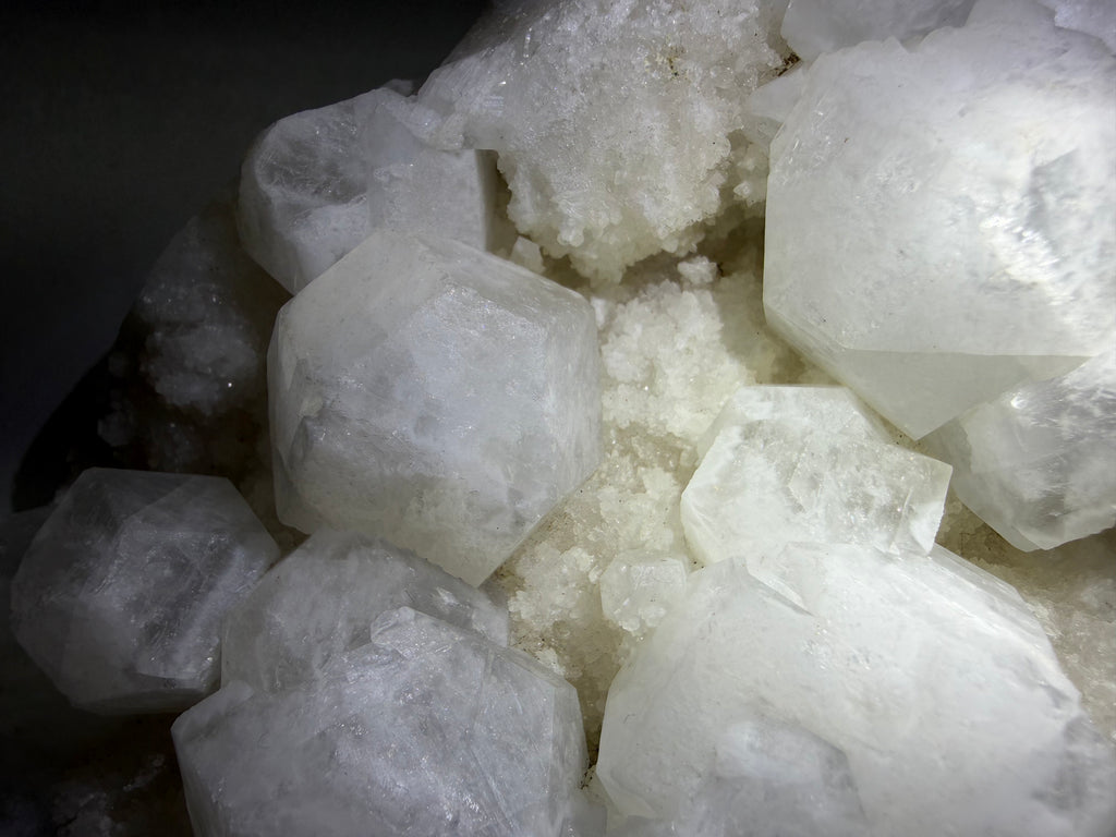 A close-up of translucent white crystal formations with rough faceted edges and a cloudy, mineral-like texture.