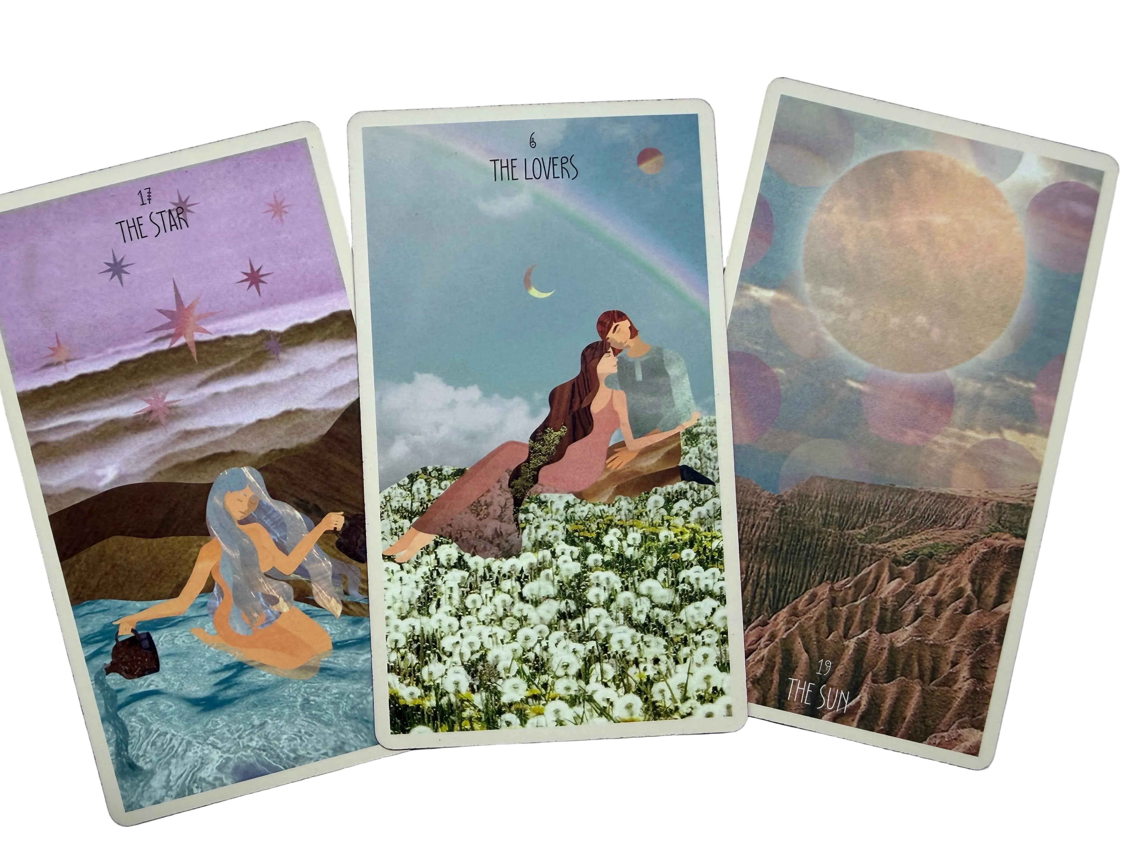 Three illustrated tarot-style cards fanned out on a light gray textured surface. The left card reads 'The Star' with a purple sky and a woman in water; the center card reads 'The Lovers' with a rainbow, moon, and seated figures in a field of white flowers; the right card reads 'The Sun' with a large glowing sun and rocky landscape.
