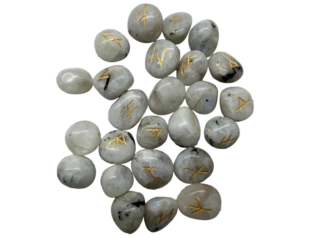 A pile of small polished white tumbled stones with engraved gold runic symbols, arranged on a light gray textured background.