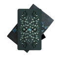 Card with floral design on a dark background surrounded by foliage