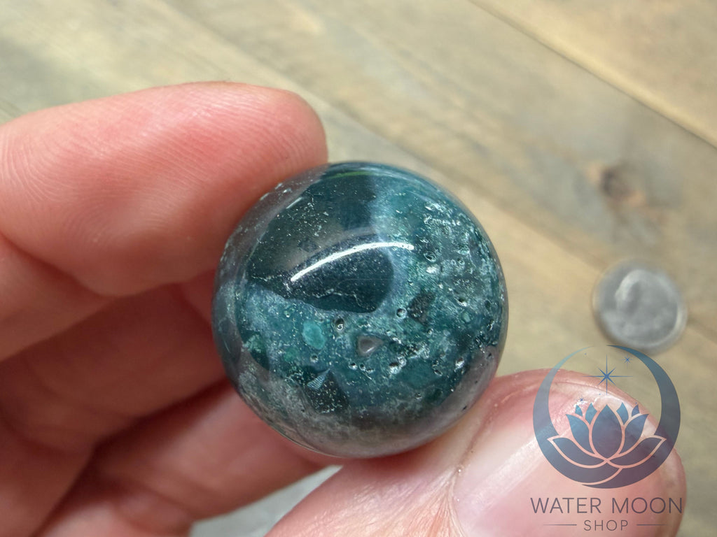 Hand holding a blue-green marbled stone with a blurred background