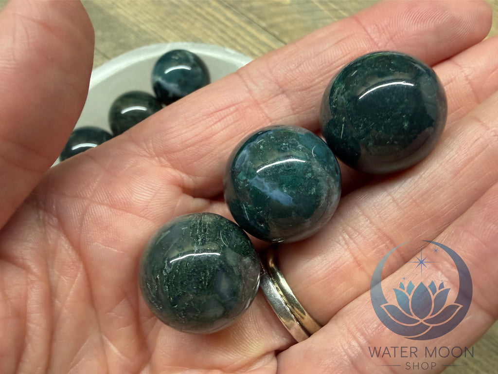 Hand holding three green stones with a blurred background