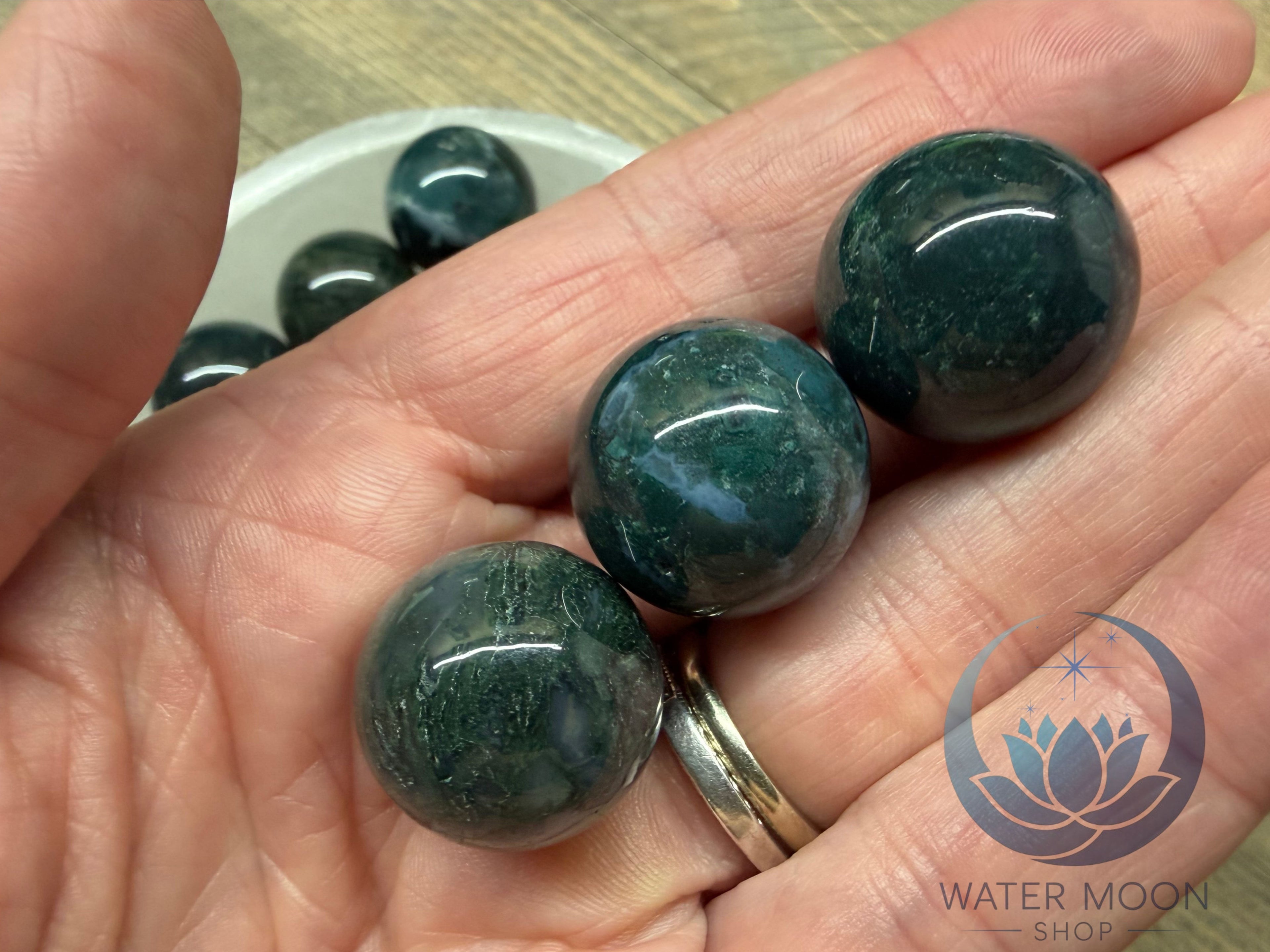 Hand holding three green stones with a blurred background