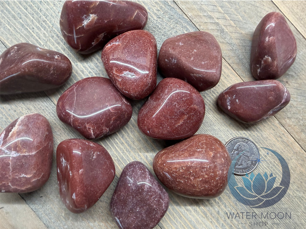 Red marbled stones on a wooden surface with a quarter for scale.