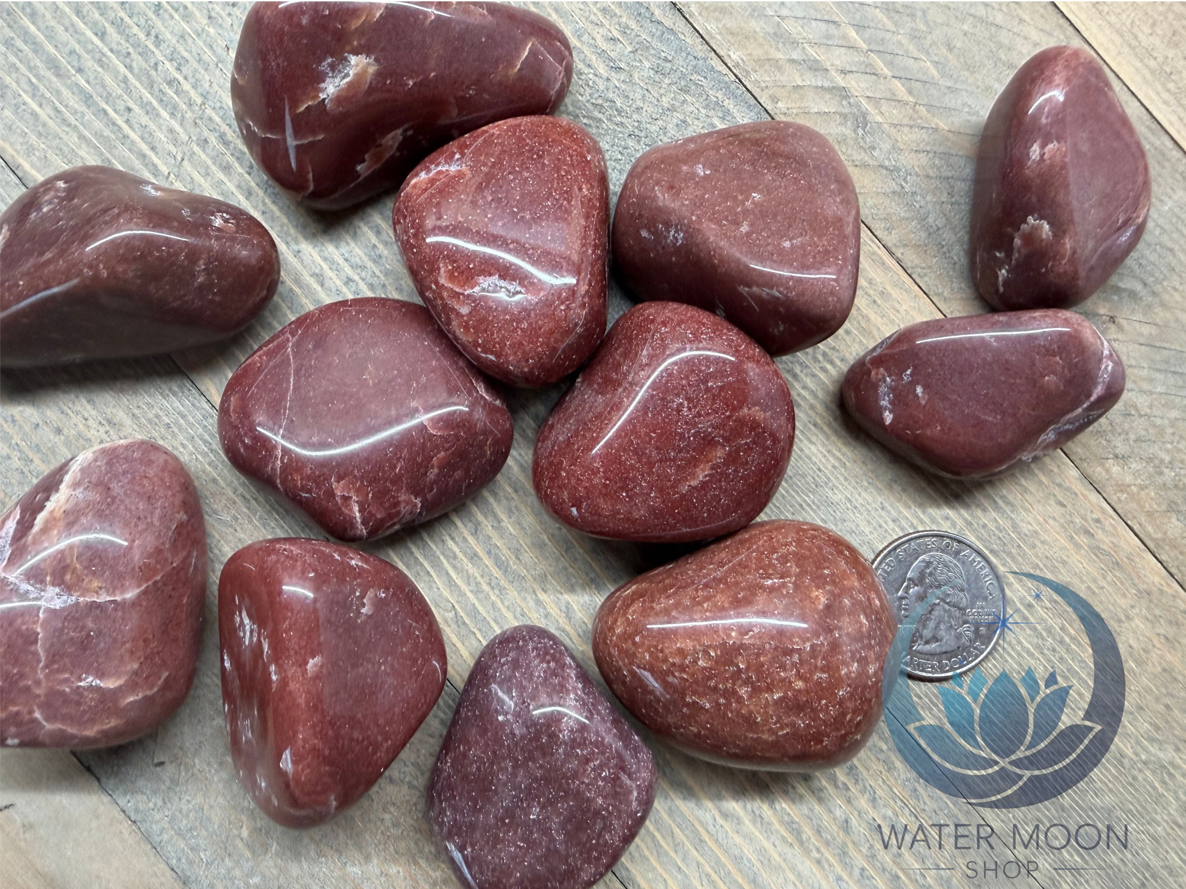 Red marbled stones on a wooden surface with a quarter for scale.